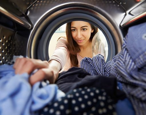Woman Doing Laundry Reaching Inside Washing Machine