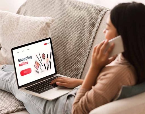 Female Shopping Concept. Back view of woman browsing online make up store, talking on phone, sitting at home