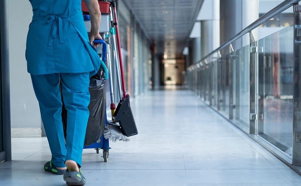 A woman worker in special clothes rolls a trolley for cleaning offices. Cleanroom concept during quarantine. Place for text
