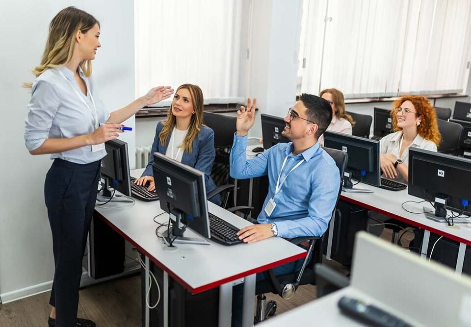 Female educator and students in programming school discuss during the class. Male student asking a question