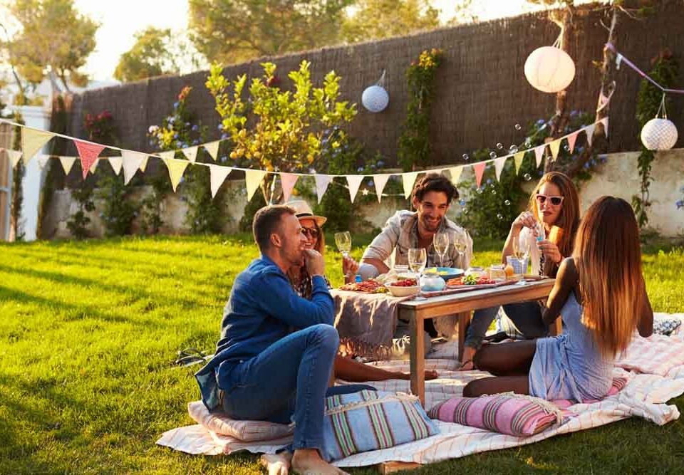 Group Of Friends Enjoying Outdoor Picnic In Garden
